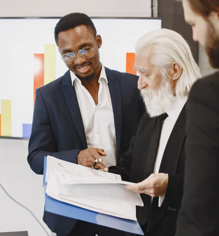 Three men are discussing and pointing at a contract for buying a house.