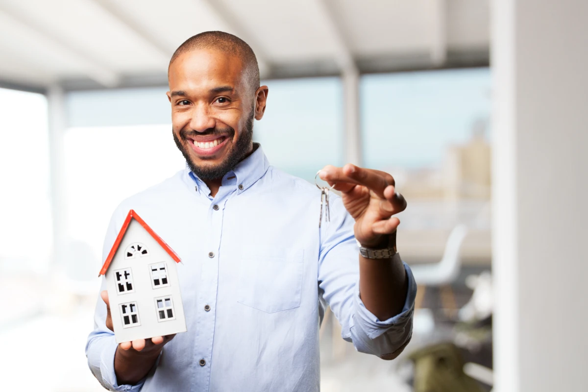 A man with a smile on his face holding a miniature house model.