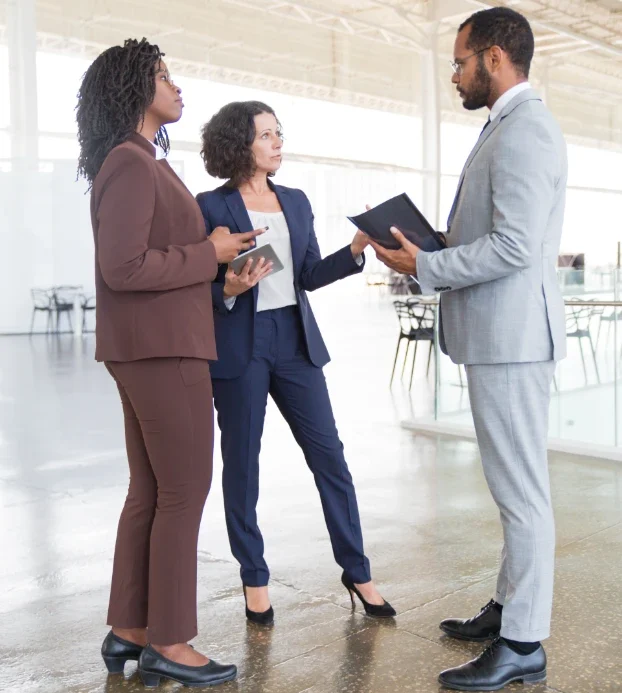 Three business people, including American and African individuals, are discussing in an office at a property management company.